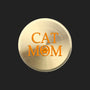 A round, brushed gold metal sign or plaque featuring the text 'CAT MOM' in orange, with the letter 'O' stylized as a paw print, set against a plain white background.