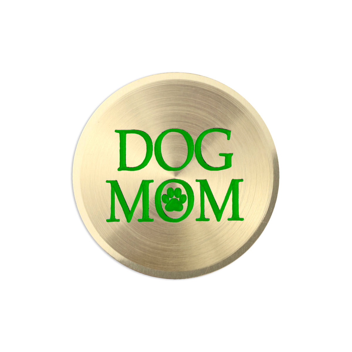 A round, brushed gold metal button or badge featuring the text 'DOG MOM' in bright green, with the letter 'O' replaced by a green paw print icon, shown on a plain white background.