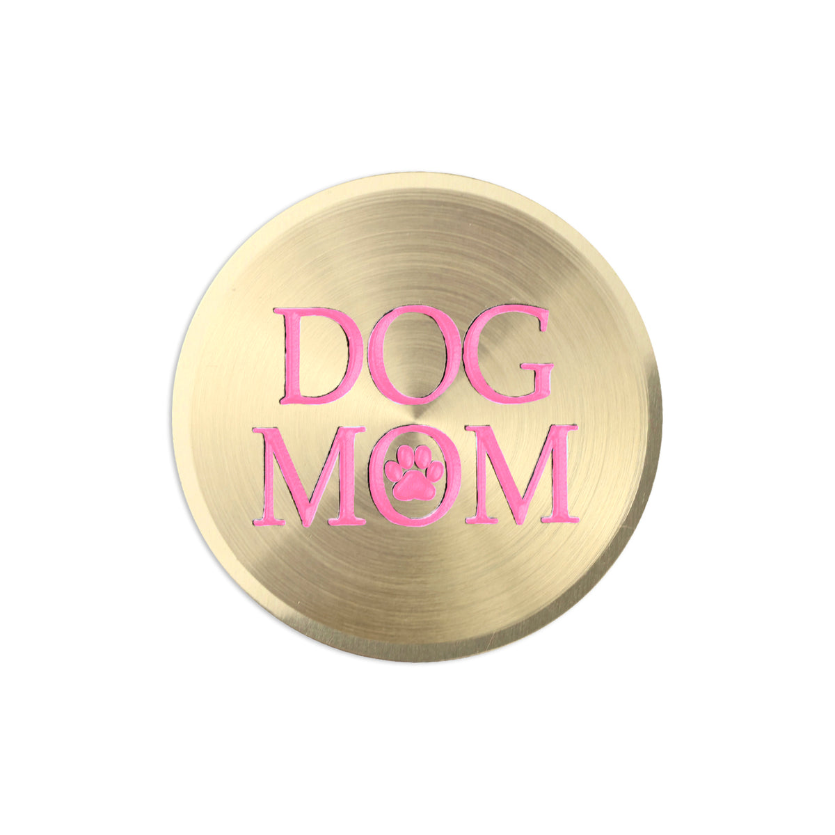 A round, brushed gold metal sticker featuring the words 'DOG MOM' in pink lettering with a paw print detail inside the letter 'O', set against a plain white background.