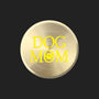 A round, brushed gold metal sticker featuring the text 'DOG MOM' in bright yellow, with the letter 'O' stylized as a paw print, set against a plain white background.