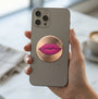A round, brushed metallic gold sticker featuring a graphic illustration of glossy magenta pink lips in the center, shown on a plain white background.