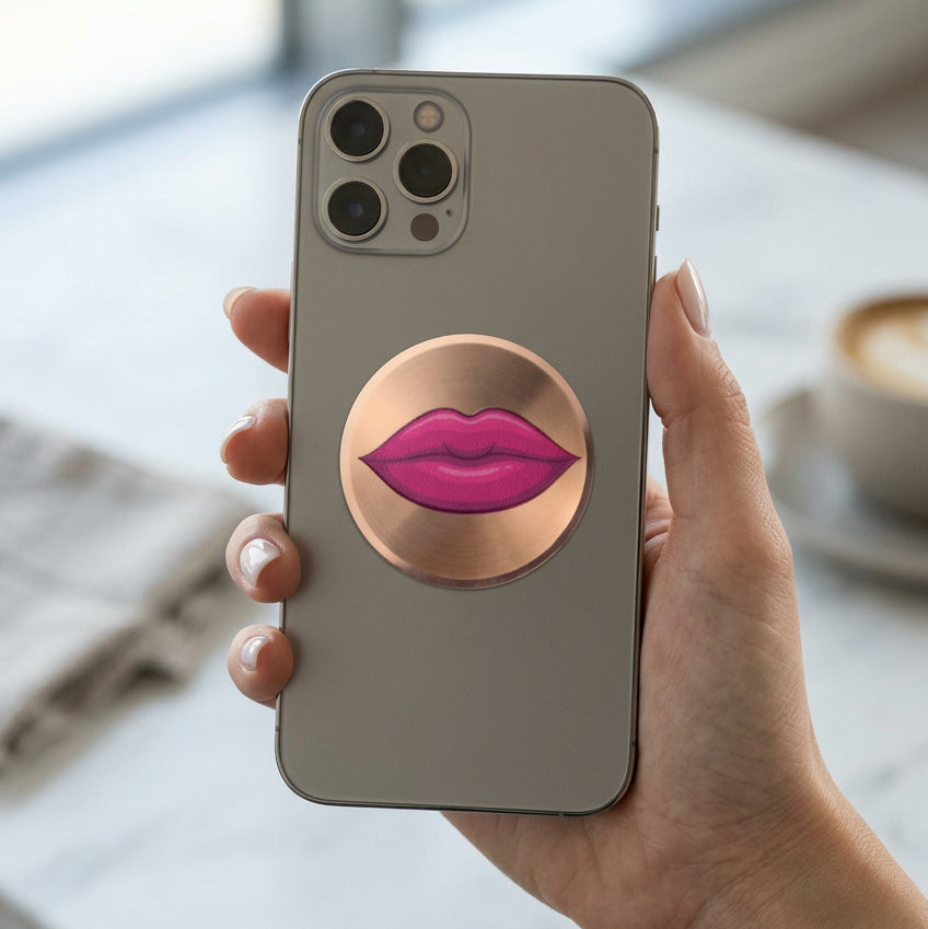 A round, brushed metallic gold sticker featuring a graphic illustration of glossy magenta pink lips in the center, shown on a plain white background.