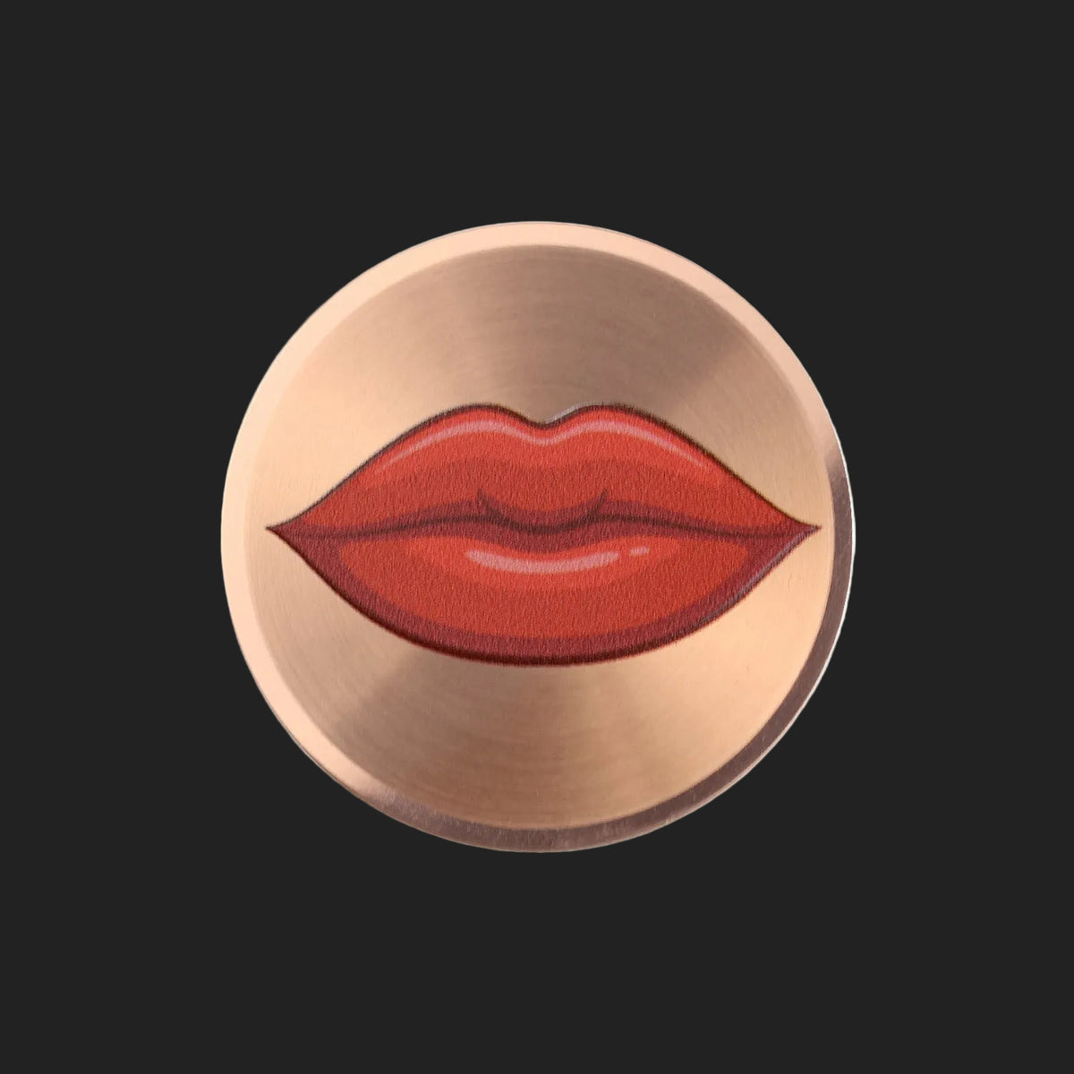 A circular metallic rose gold sticker featuring an illustration of red lips in the center, set against a plain white background.