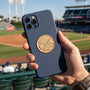 Metal Stickems baseball themed gold metal sticker applied to a navy blue smartphone case at a baseball stadium.