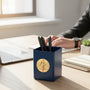 Metal Stickems businessman cityscape gold metal sticker applied to a navy blue desk pen holder in an office setting.