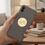 Metal Stickems round gold cyclist sticker applied to the back of a grey smartphone held in a hand.