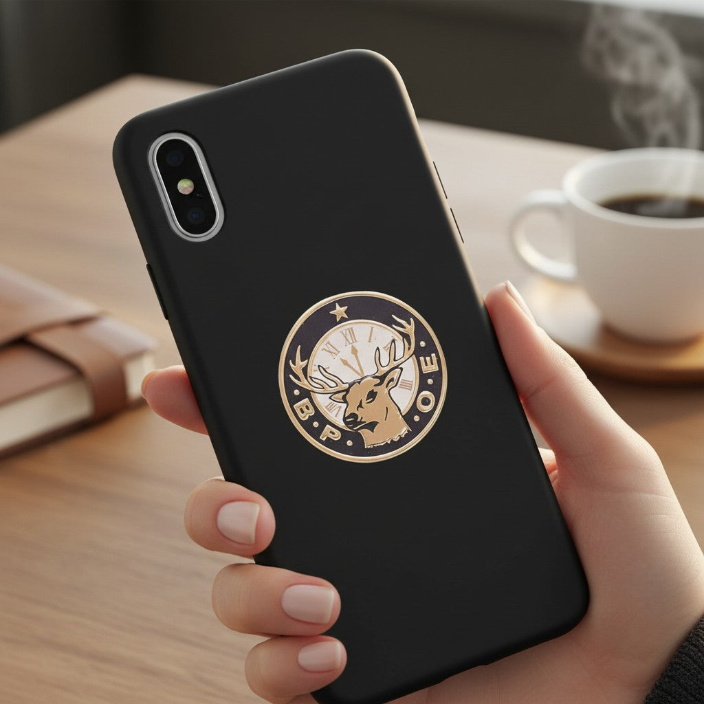 Metal Stickems elk and clock decorative metal badge applied to the back of a black smartphone case.