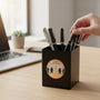 Metal Stickems Employee Of The Month round gold metal sticker applied to a black desk pen holder