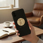 Metal Stickems gold archery sticker featuring an embossed archer design applied to a black smartphone case
