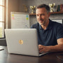 Metal Stickems gold basketball action sticker applied to the lid of a laptop used by a man in an office setting