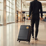 Metal Stickems gold basketball player emblem applied to a black suitcase carried by a man in an airport terminal