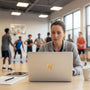 Metal Stickems 2-inch gold basketball achievement sticker applied to the lid of a laptop in a gym setting.