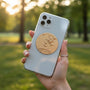 Metal Stickems gold-toned circular metal sticker featuring a flying bird relief design applied to a smartphone case.