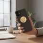 Metal Stickems gold eagle emblem sticker applied to the back of a black smartphone held in a hand.