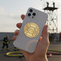 Metal Stickems gold-tone fire department Maltese cross metal sticker applied to the back of a smartphone.