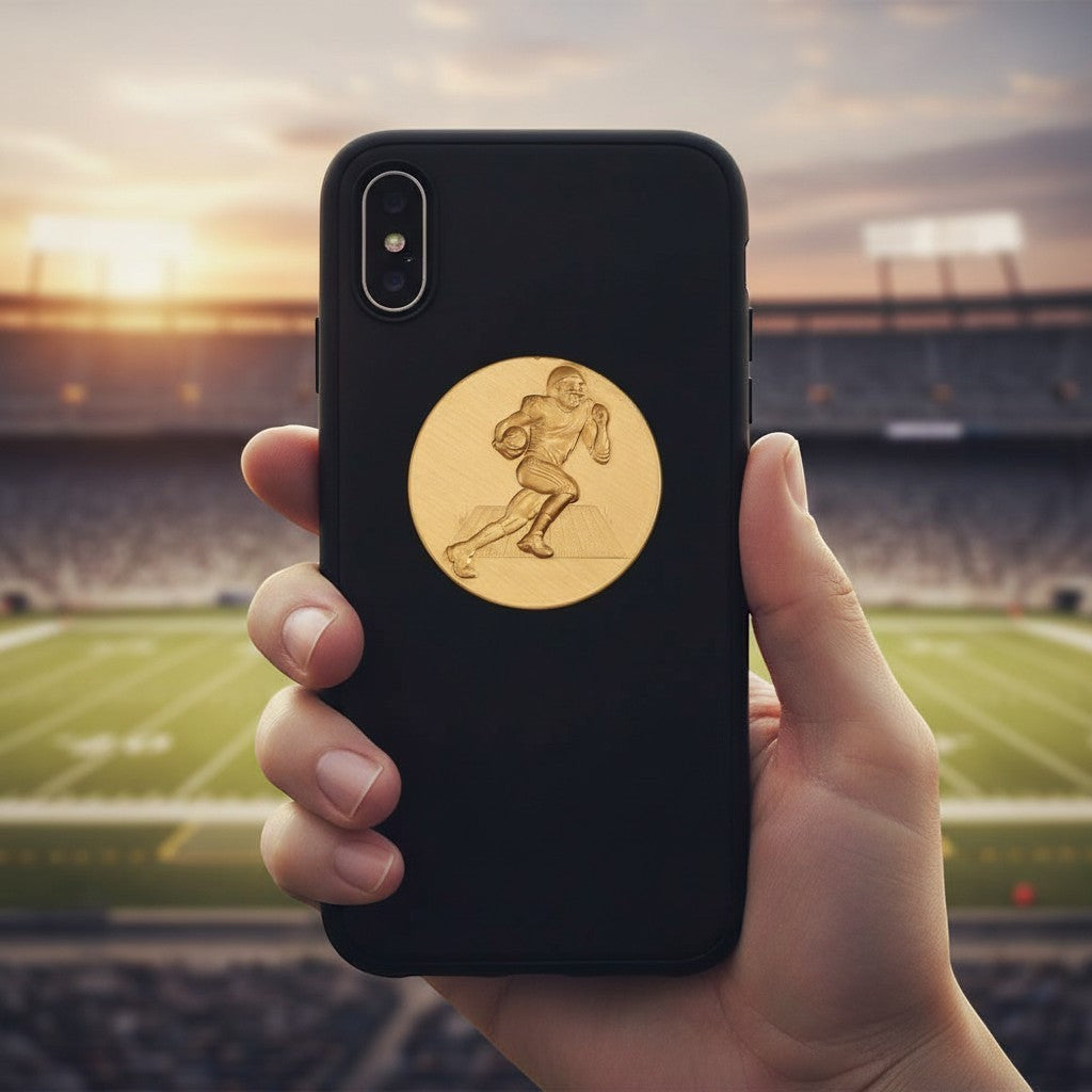 Metal Stickems gold football player metal sticker applied to a black smartphone case with a stadium background.