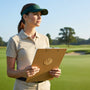 Metal Stickems gold golf emblem sticker featuring crossed clubs and ball on a clipboard held by a woman on a golf course