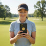 Metal Stickems gold golf emblem sticker applied to a smartphone held by a woman on a golf course.