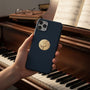 Metal Stickems 2-inch gold-tone embossed grand piano sticker applied to a navy blue smartphone case