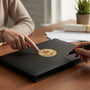 Metal Stickems 2-inch gold handshake and star metal emblem applied to a black leather notebook on a wooden desk.