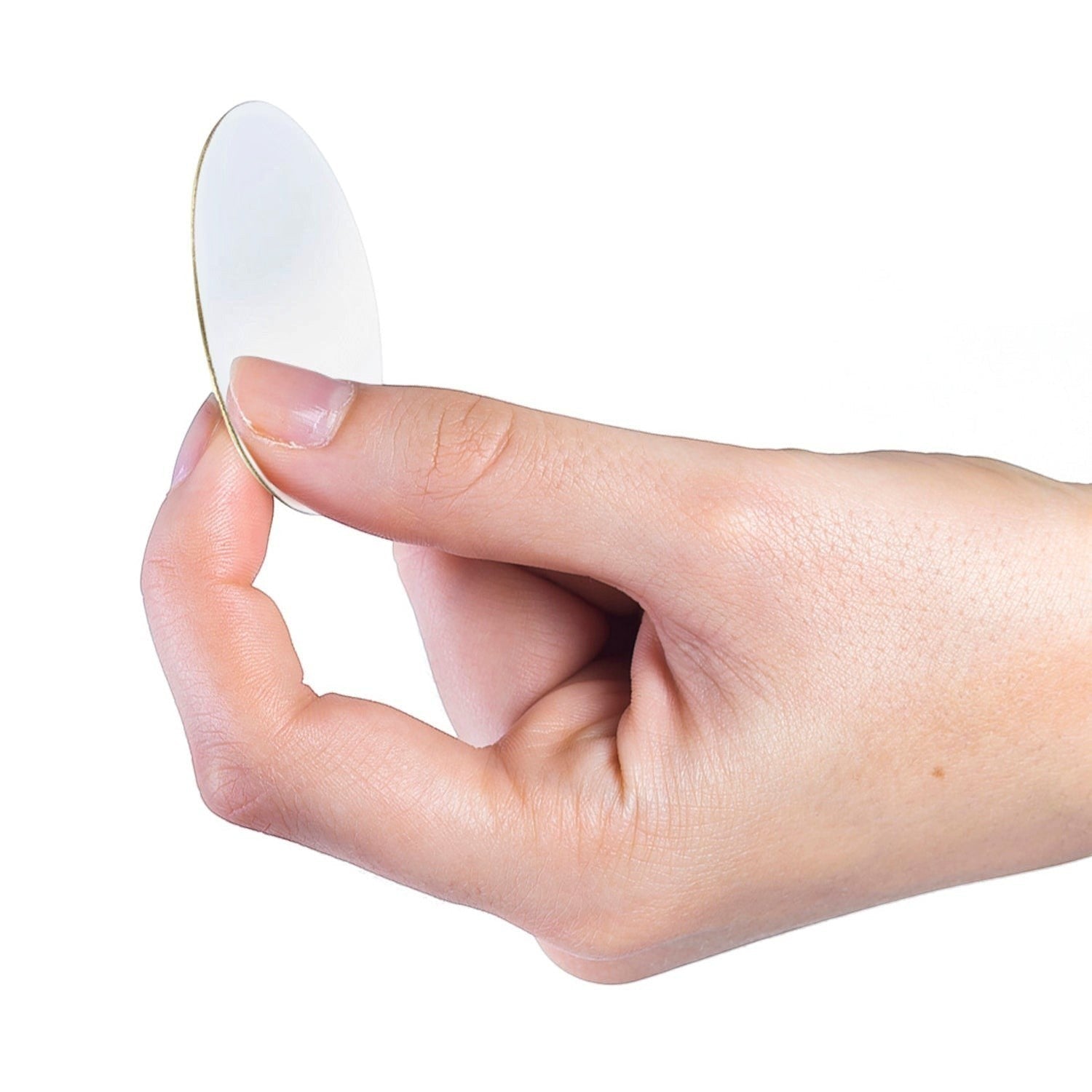 Metal Stickems 1-inch circular gold-tone metal sticker held between fingers showing the adhesive backing