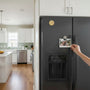 Metal Stickems gold embossed cross country runner sticker applied to a black refrigerator in a modern kitchen