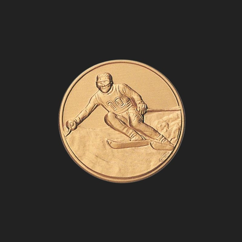 Metal Stickems 1-inch gold-toned metal sticker featuring an embossed skier in action for gear customization.