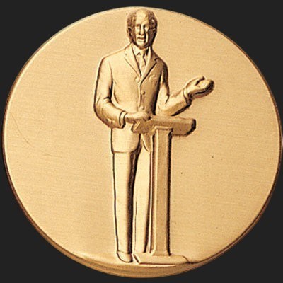 Metal Stickems 2-inch gold adhesive medallion featuring a raised relief design of a speaker at a podium.