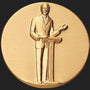 Metal Stickems 2-inch gold adhesive medallion featuring a raised relief design of a speaker at a podium.