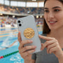 Metal Stickems gold swimming athlete medallion sticker applied to the back of a smartphone held by a smiling woman
