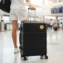 Metal Stickems gold tennis player embossed metal sticker applied to a black suitcase in an airport terminal.