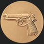 Metal Stickems 2-inch round gold-tone metal sticker featuring an embossed handgun design for tactical gear.