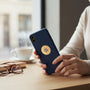 Metal Stickems Military Intelligence gold metal sticker applied to a blue smartphone held by a person at a desk.