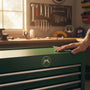 Metal Stickems 2-inch Military Police crossed pistols metal emblem in gold and green on a green tool chest drawer.