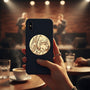 Metal Stickems 2-inch embossed metal sticker featuring musical instruments on a black smartphone case in a jazz club.