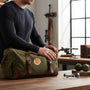 Metal Stickems 2-inch gold metallic rifle shooter emblem applied to an olive green canvas gear bag on a wooden table.