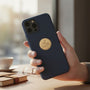 Metal Stickems gold rowing athlete emblem sticker applied to the back of a navy blue smartphone case