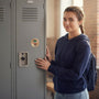 Metal Stickems softball metal sticker on a grey school locker next to a smiling girl in a blue hoodie