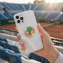 Metal Stickems tennis court metal sticker on a white smartphone case held in front of a blurred tennis stadium.