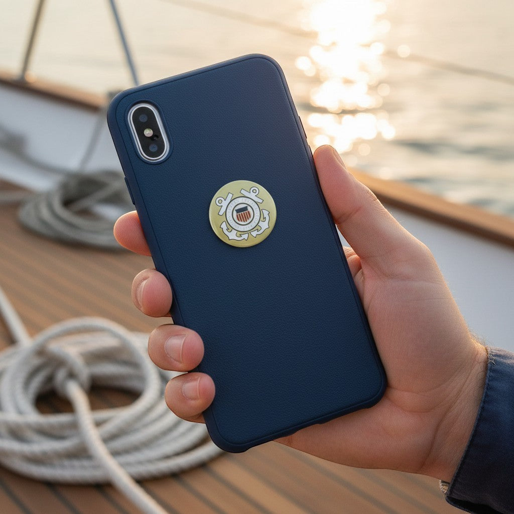 Metal Stickems 7/8 inch United States Coast Guard metal emblem sticker applied to a navy blue smartphone case.