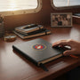 Metal Stickems 2-inch USMC Eagle Globe and Anchor metal sticker applied to a black notebook on a wooden desk.