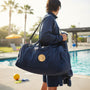 Metal Stickems water polo metal emblem sticker applied to a navy blue sports duffel bag at a swimming pool.
